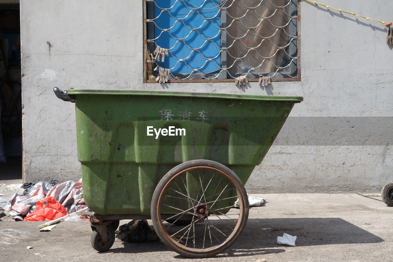 Garbage cart against house on sunny day