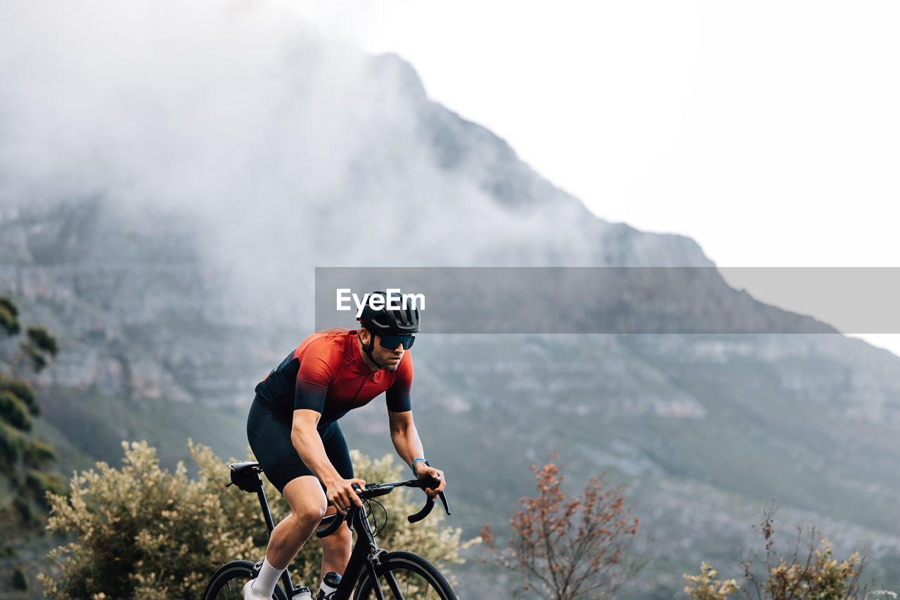 rear view of man riding bicycle against mountain