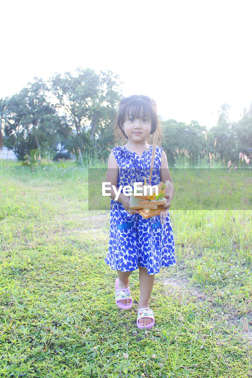 portrait of young woman standing on grassy field