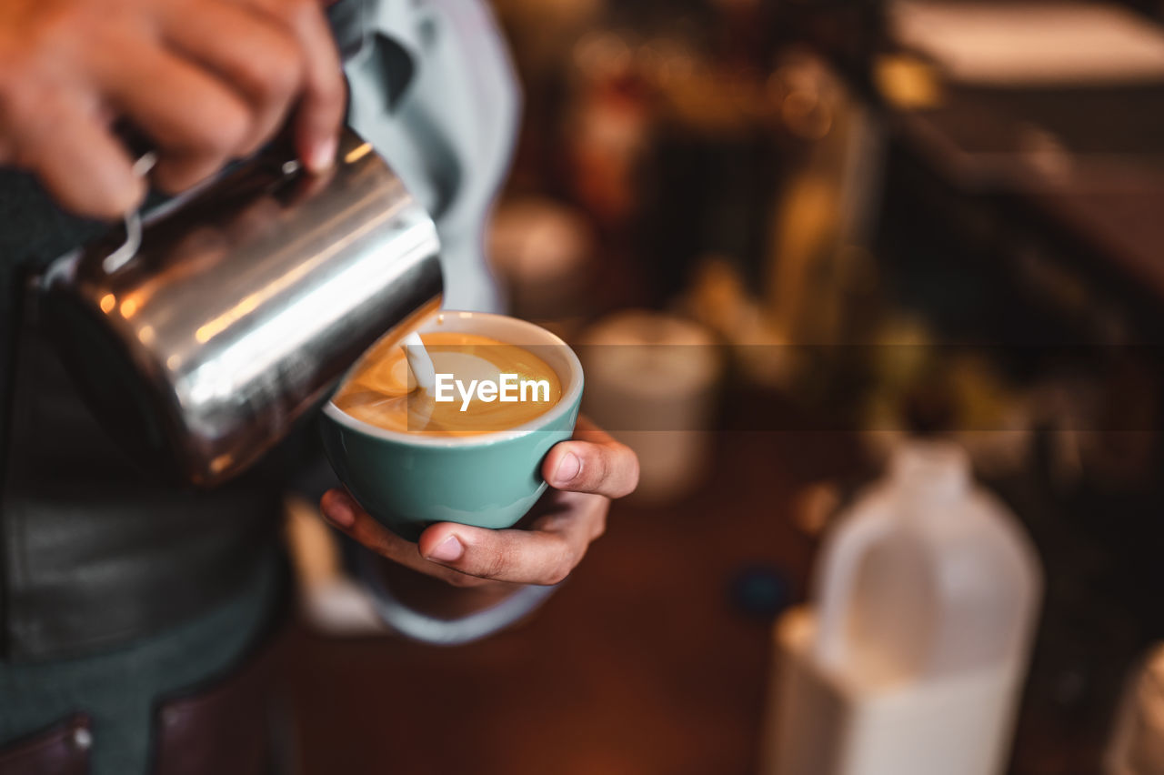 MAN POURING COFFEE IN CUP ON TABLE