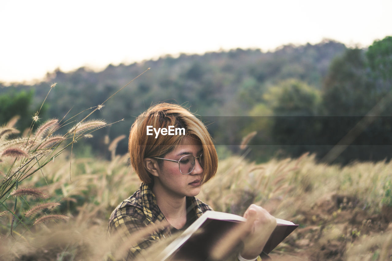 Young woman sitting reading a book at nature in the evening.