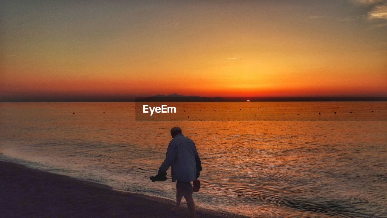 Man walking at beach during sunset