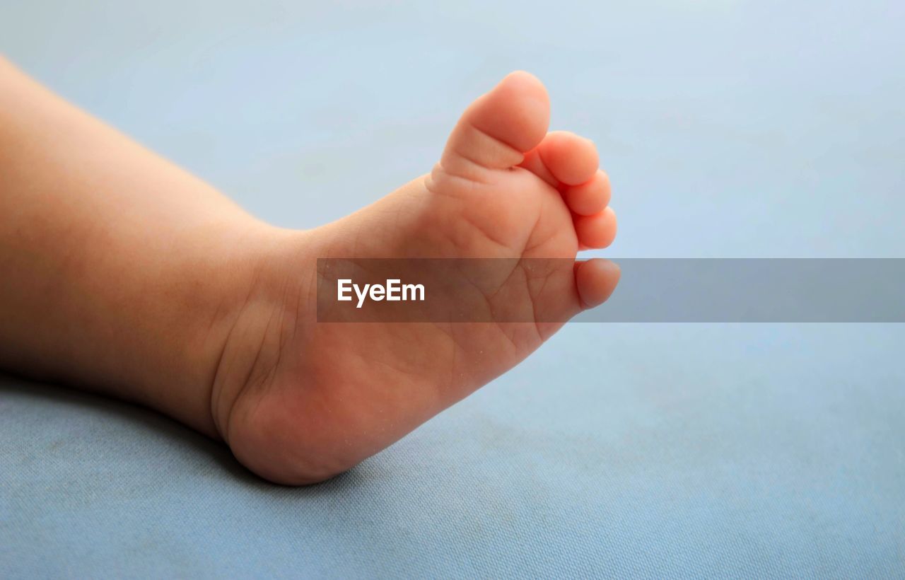 Low section of baby lying on bed