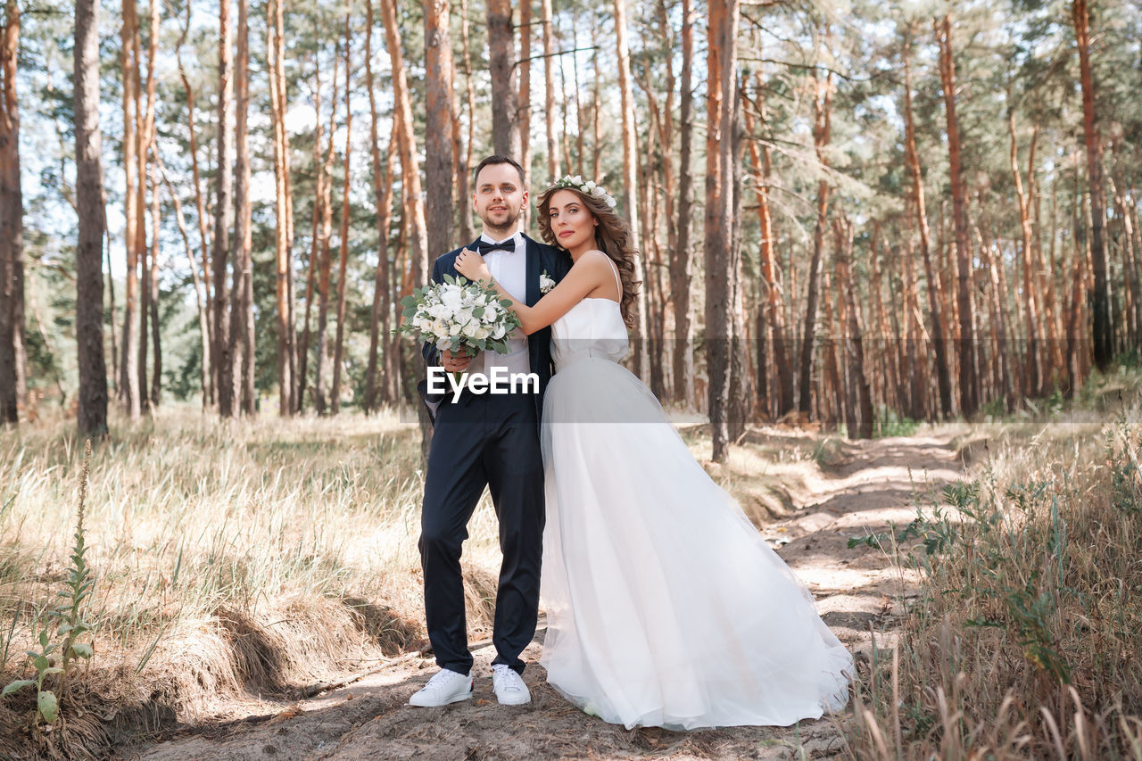 Bride and bridegroom standing on field