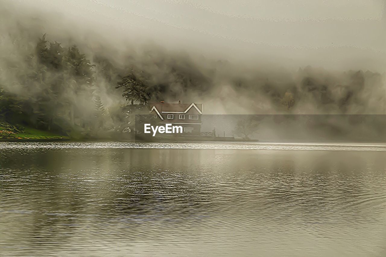 House by lake during foggy weather