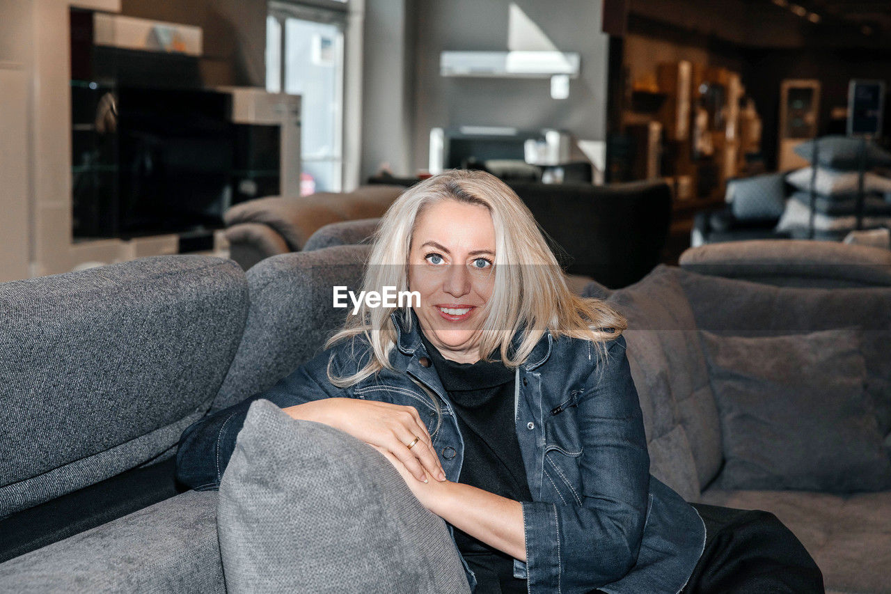 Stylish woman with gleaming silver hair relaxed in a modern furniture store