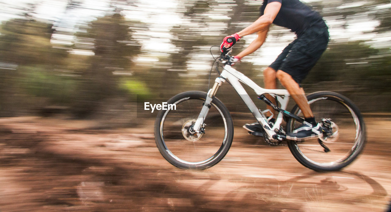 Blurred motion of man riding bicycle on dirt road