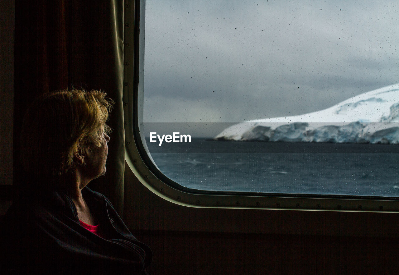 Woman looking through window while travelling in vehicle