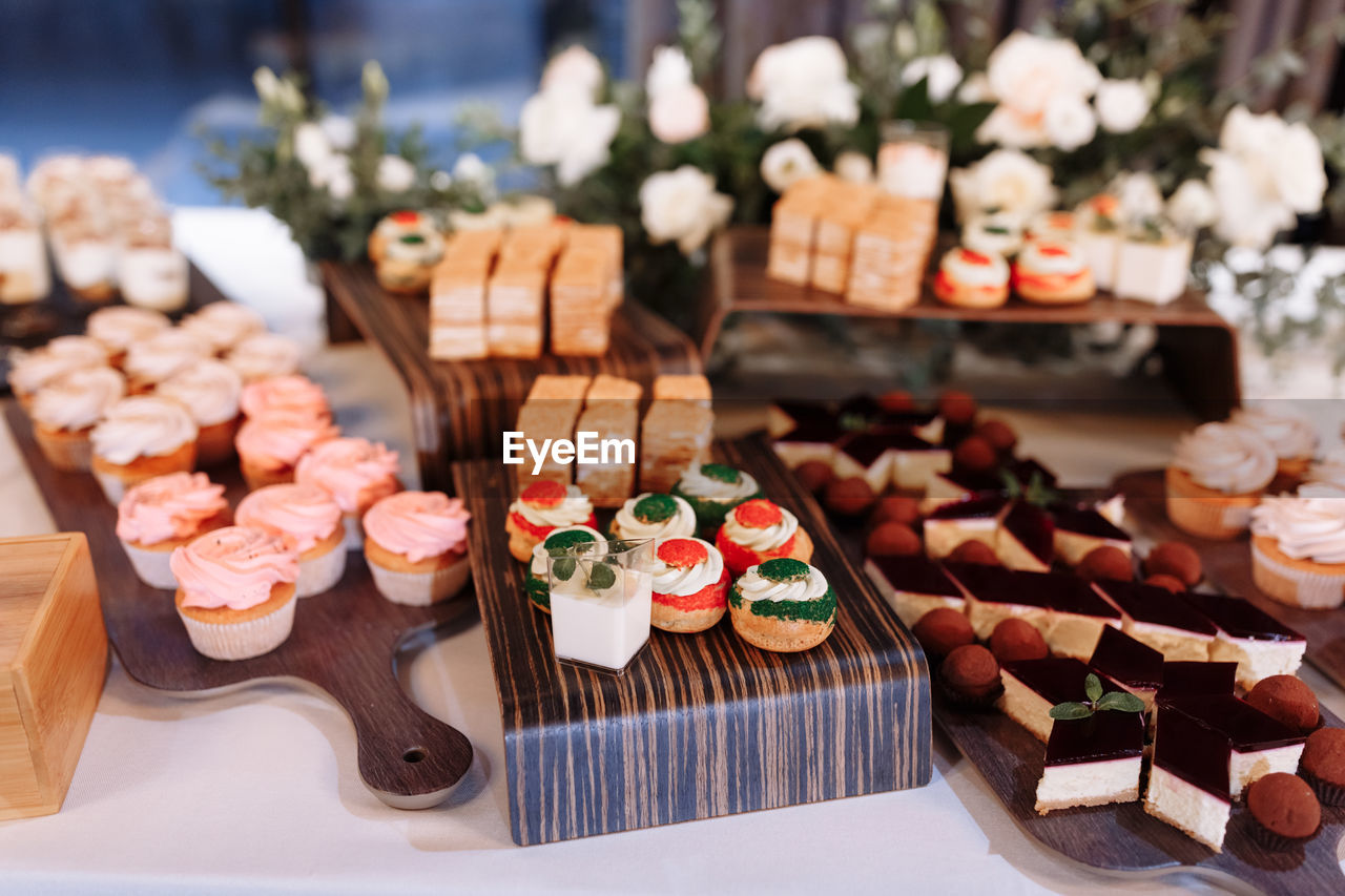 Candy bar decorated by delicious sweet buffet with cupcakes, eclairs, sweetness and flowers,