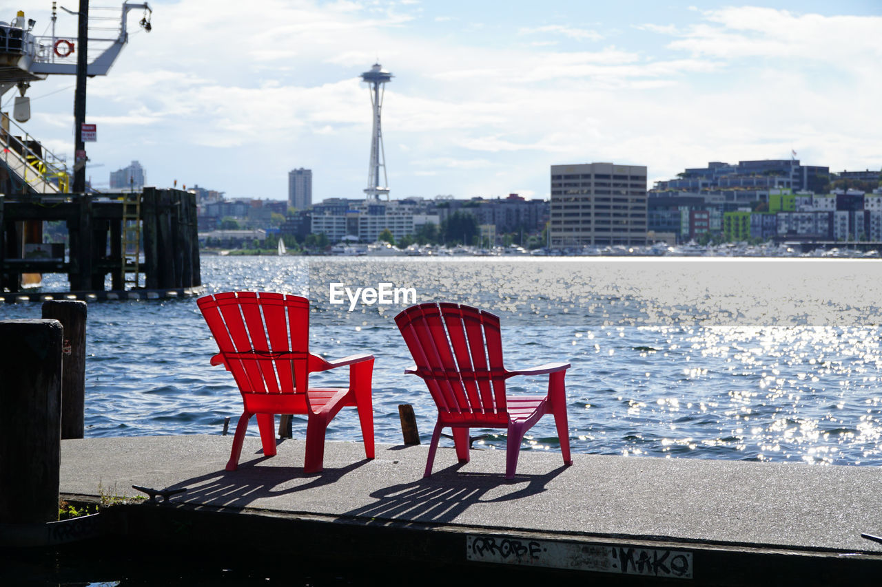 EMPTY CHAIRS AND TABLES IN CITY AGAINST SKY