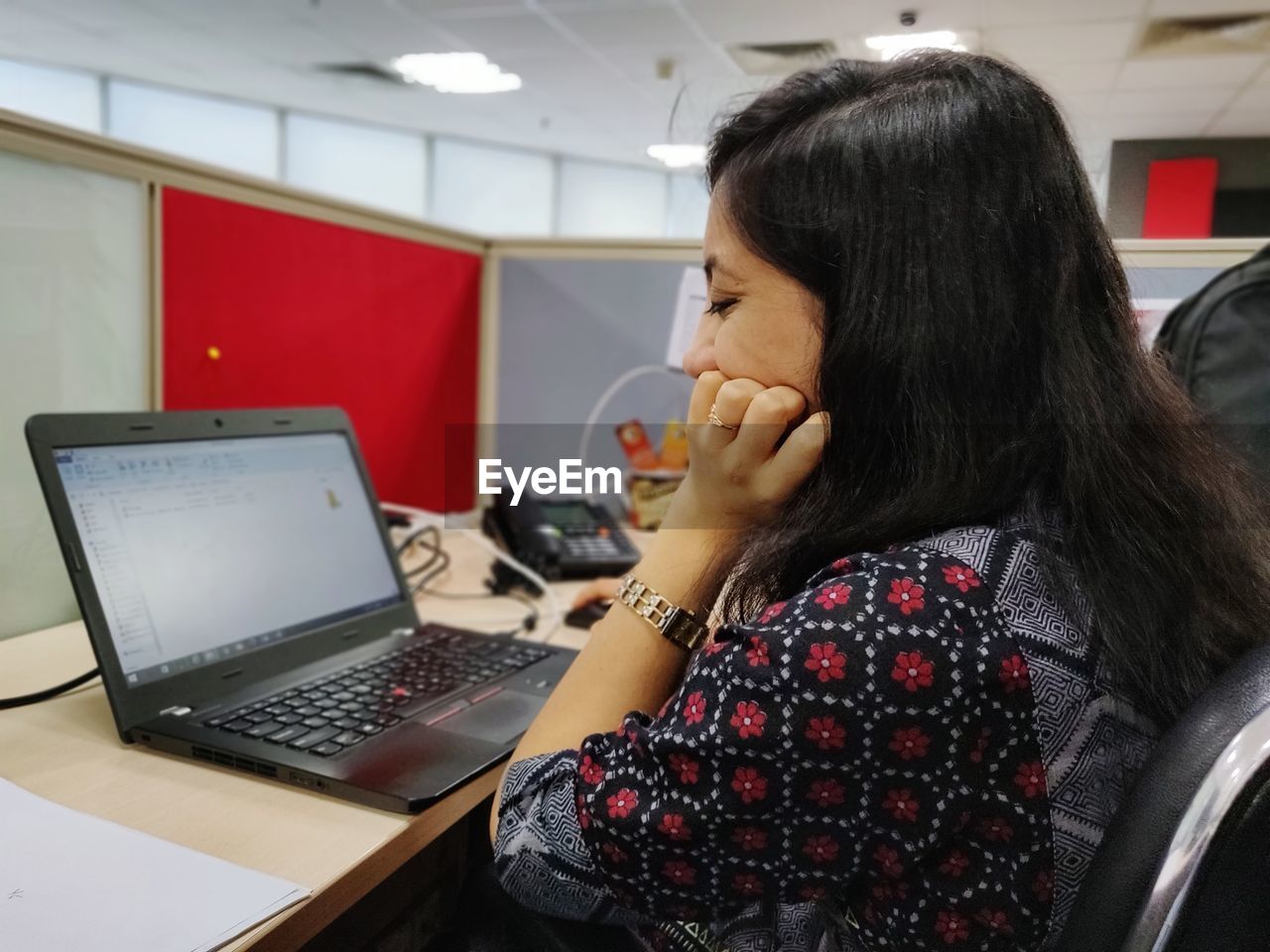 Side view of businesswoman using laptop while sitting on table at office