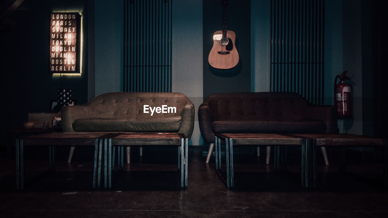 Empty sofas and tables against guitar on wall