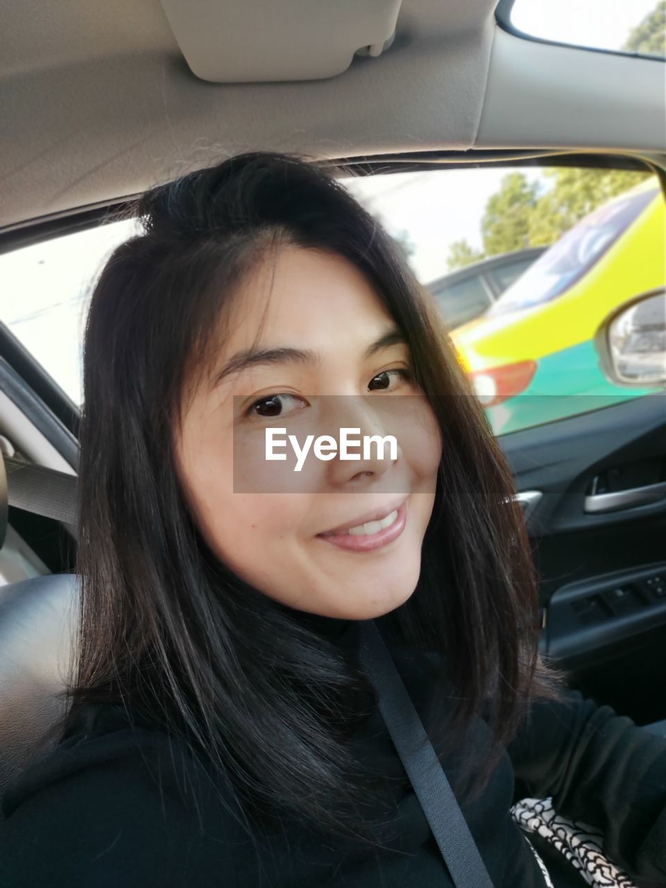 PORTRAIT OF HAPPY WOMAN IN CAR