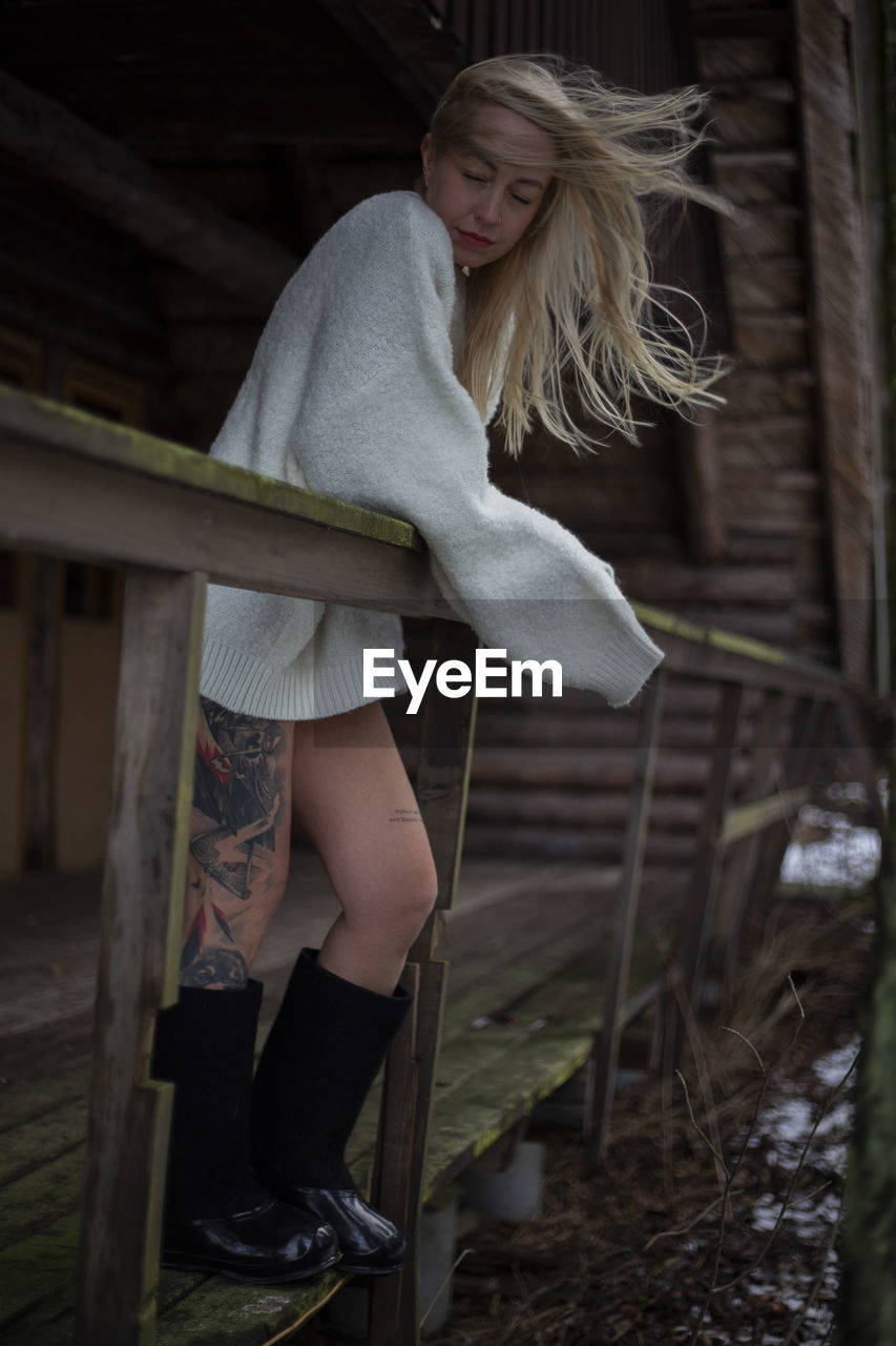 Side view of young woman standing by railing