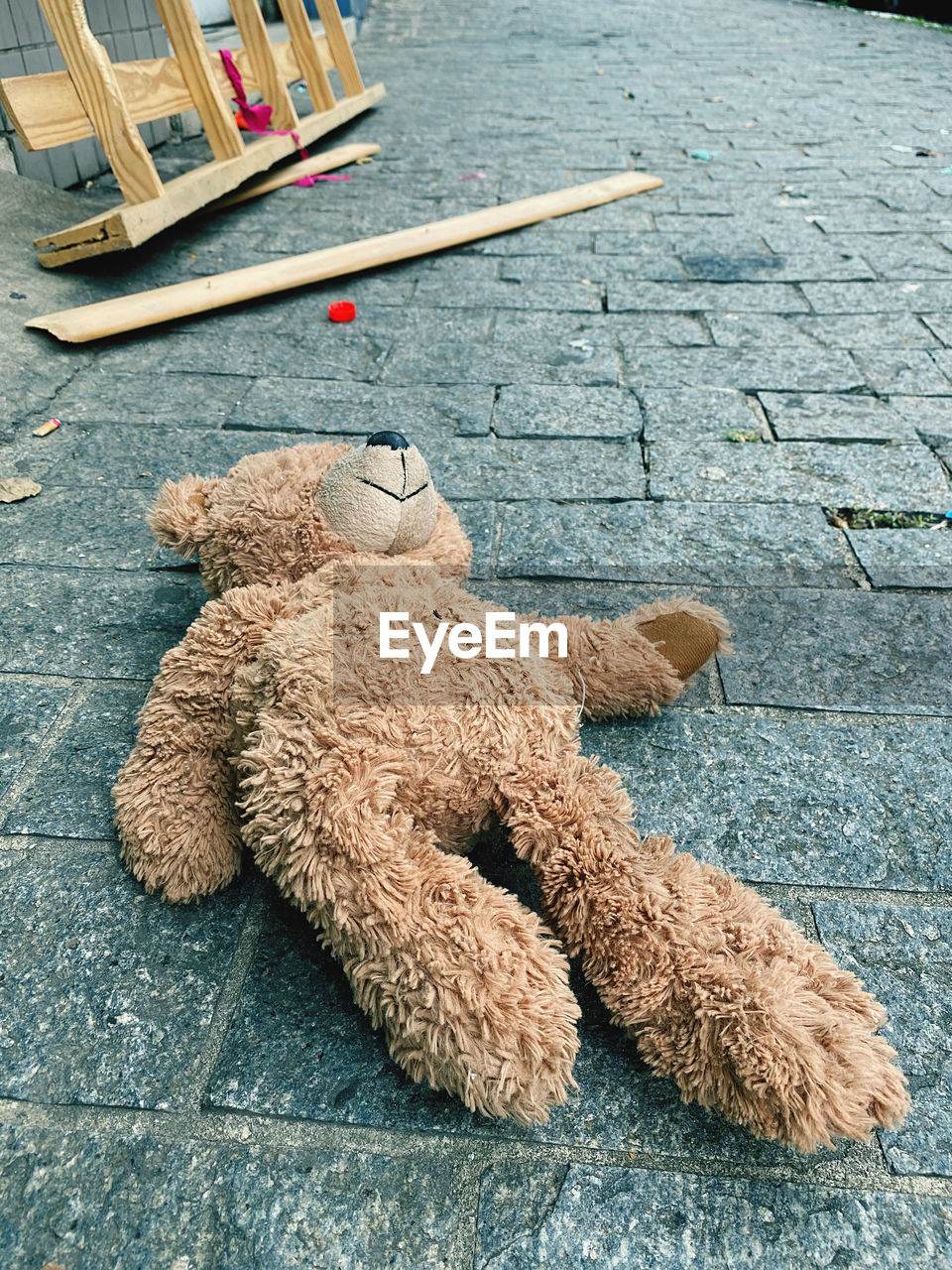 HIGH ANGLE VIEW OF STUFFED TOY ON COBBLESTONE STREET