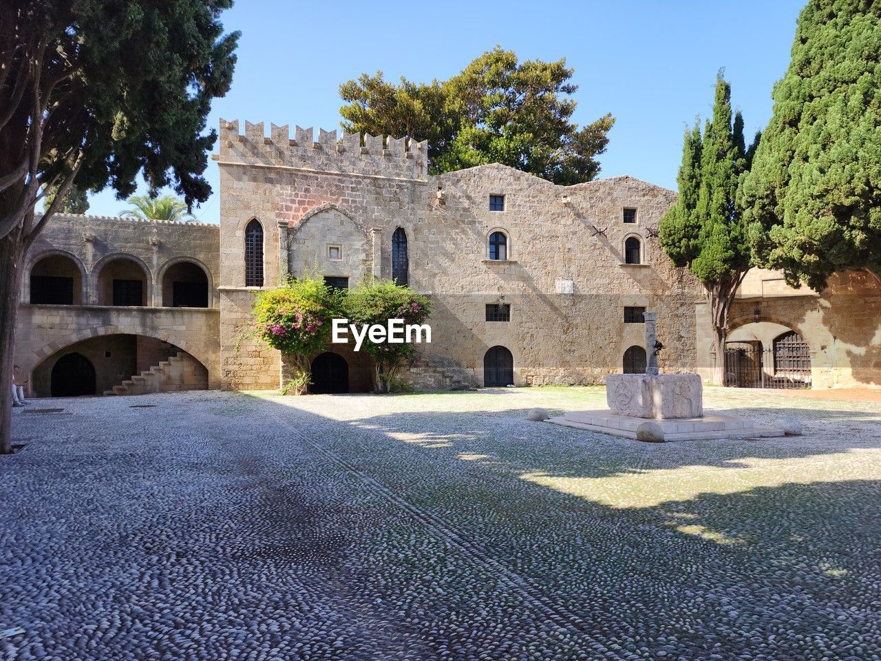 architecture, built structure, history, building exterior, the past, tree, plant, building, nature, arch, travel destinations, estate, sky, no people, travel, blue, clear sky, ancient history, ancient, city, sunlight, religion, day, tourism, outdoors, sunny, road, old, street, château, mansion