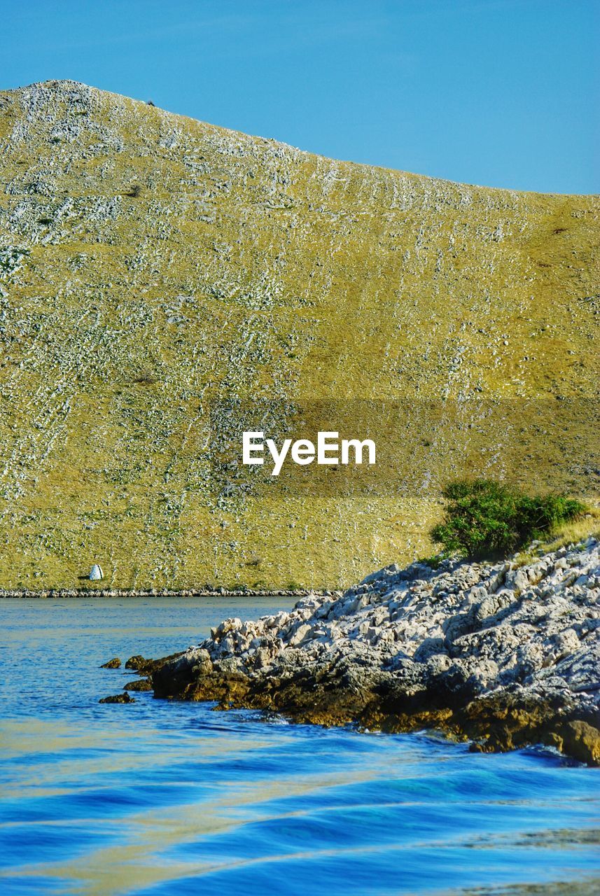 Scenic view of river and hill against clear sky