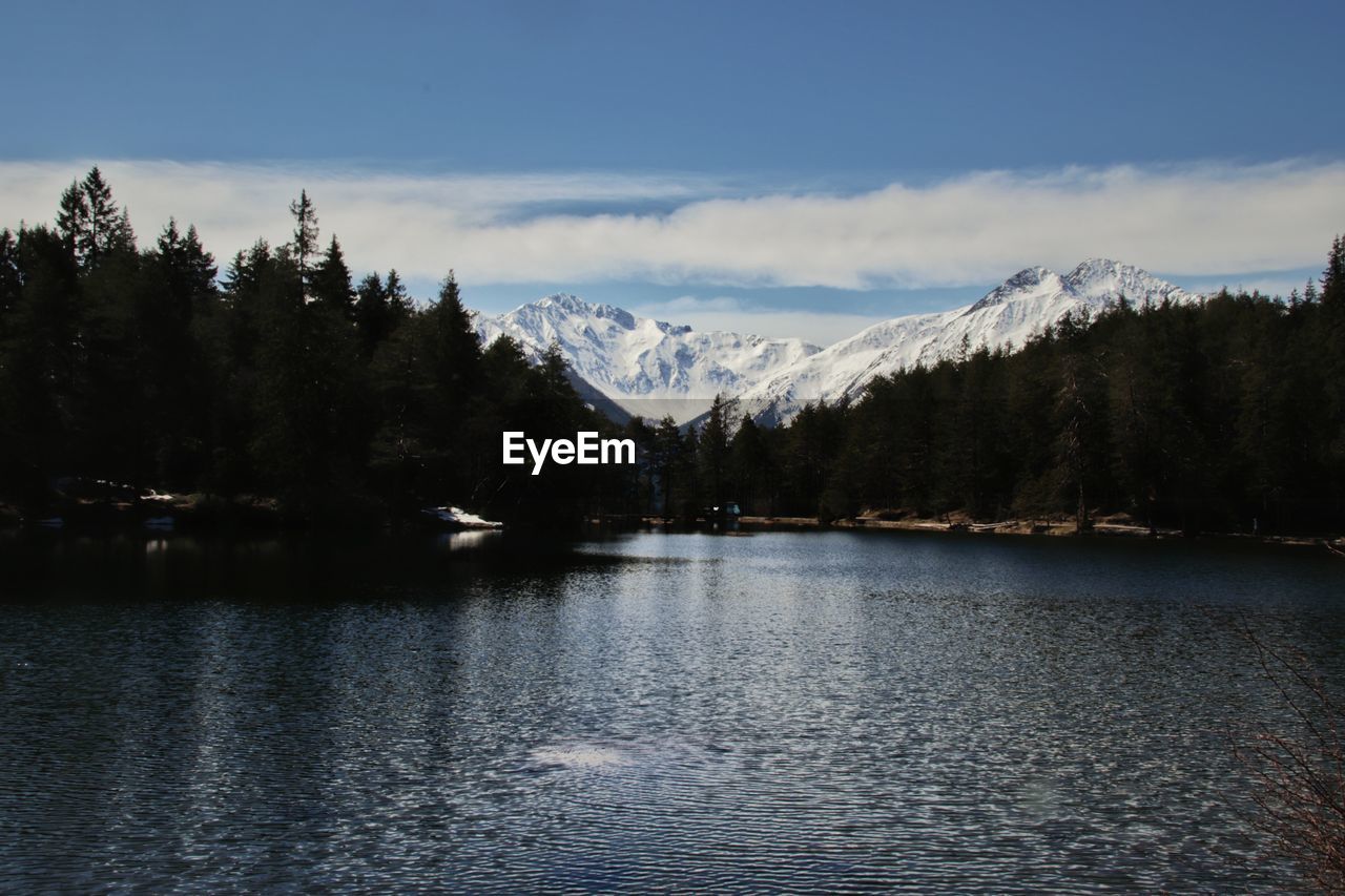 Scenic view of lake by snowcapped mountains against sky