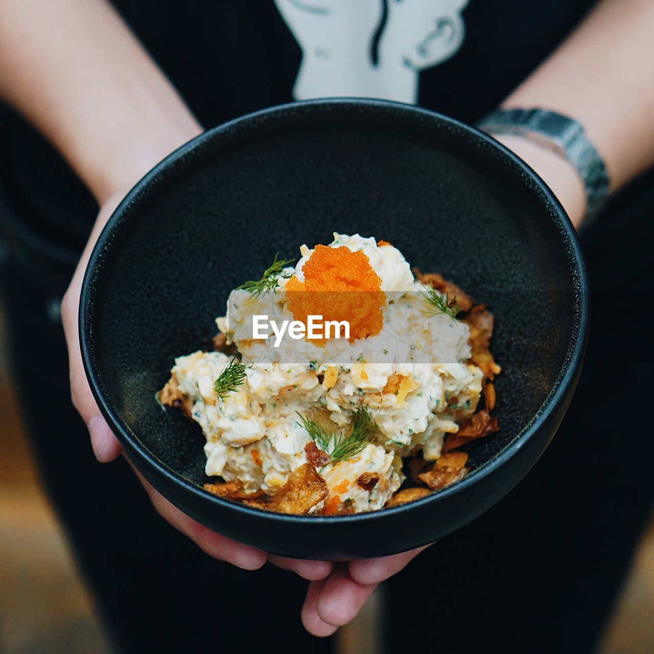 Midsection of woman holding food in bowl at home