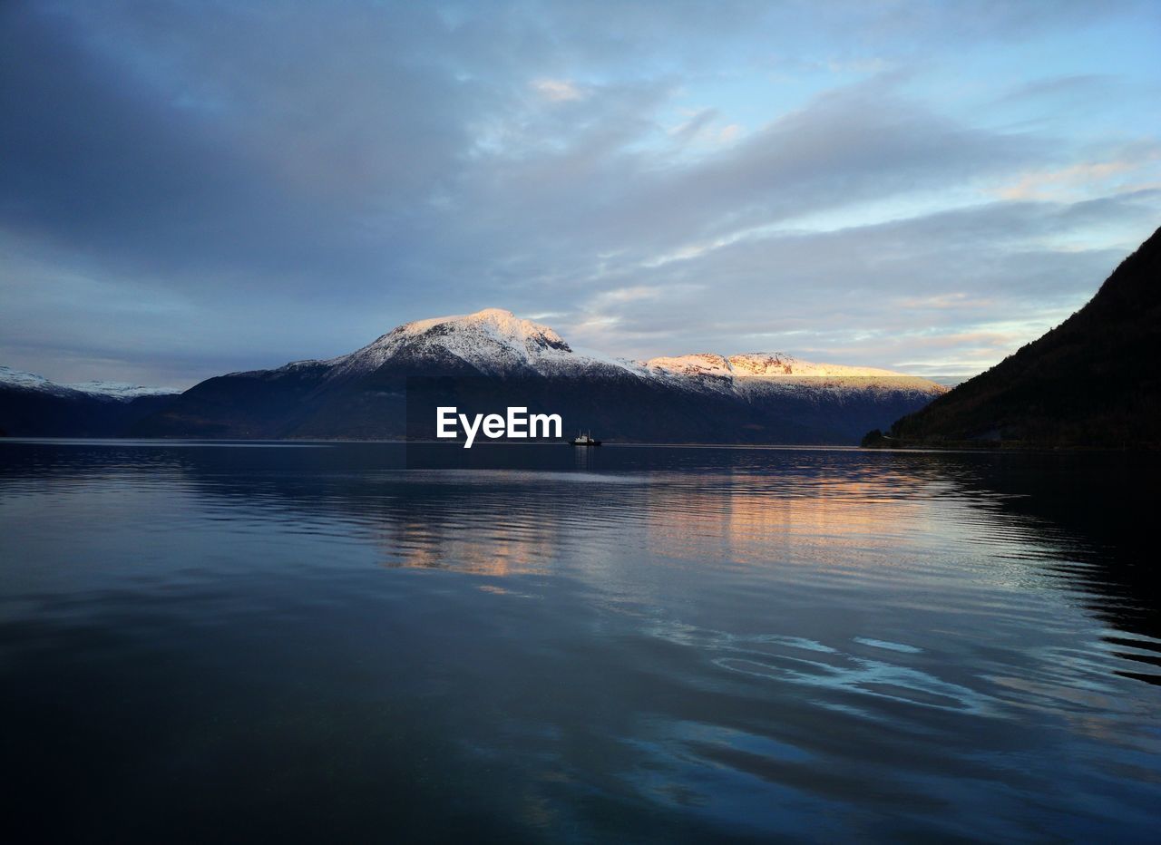 Scenic view of lake by snowcapped mountains against sky