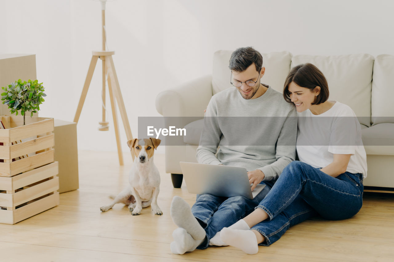 Smiling couple using laptop while sitting at home