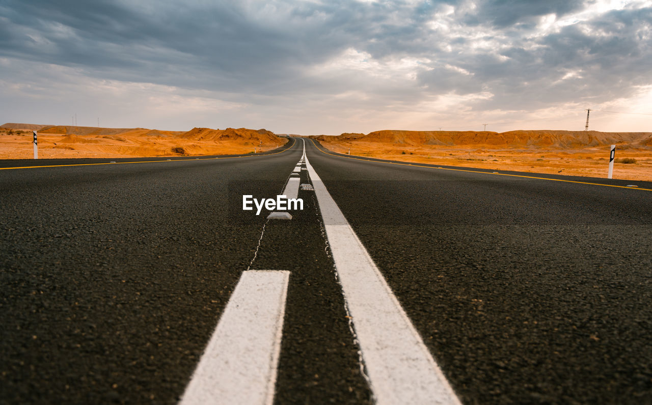 Surface level of road against sky during sunset