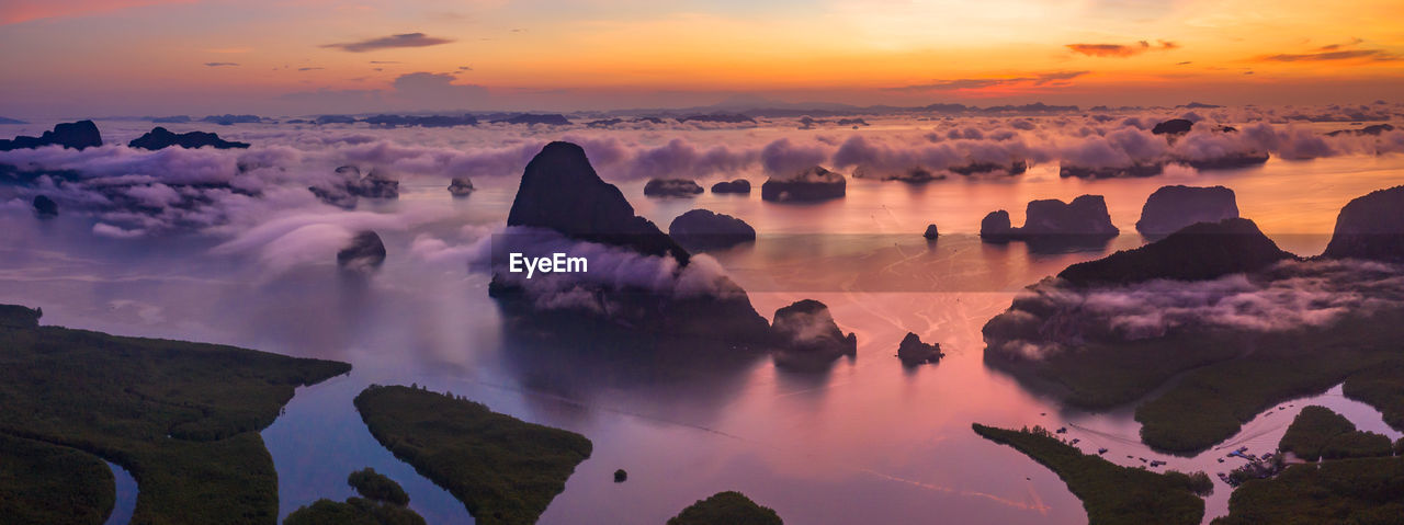 Panoramic view of rocks and sea against sky during sunset