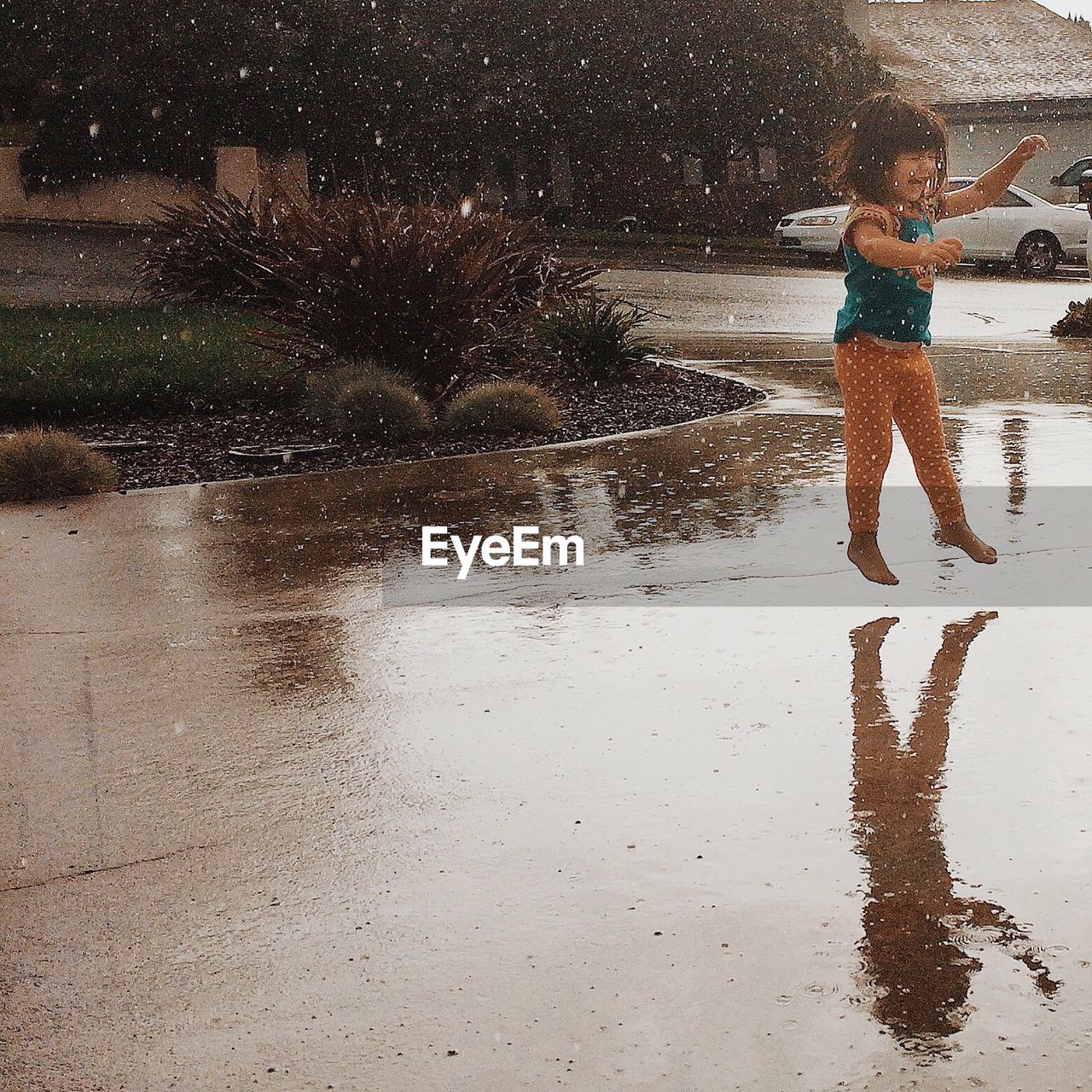 Cute girl playing on street during rainy season