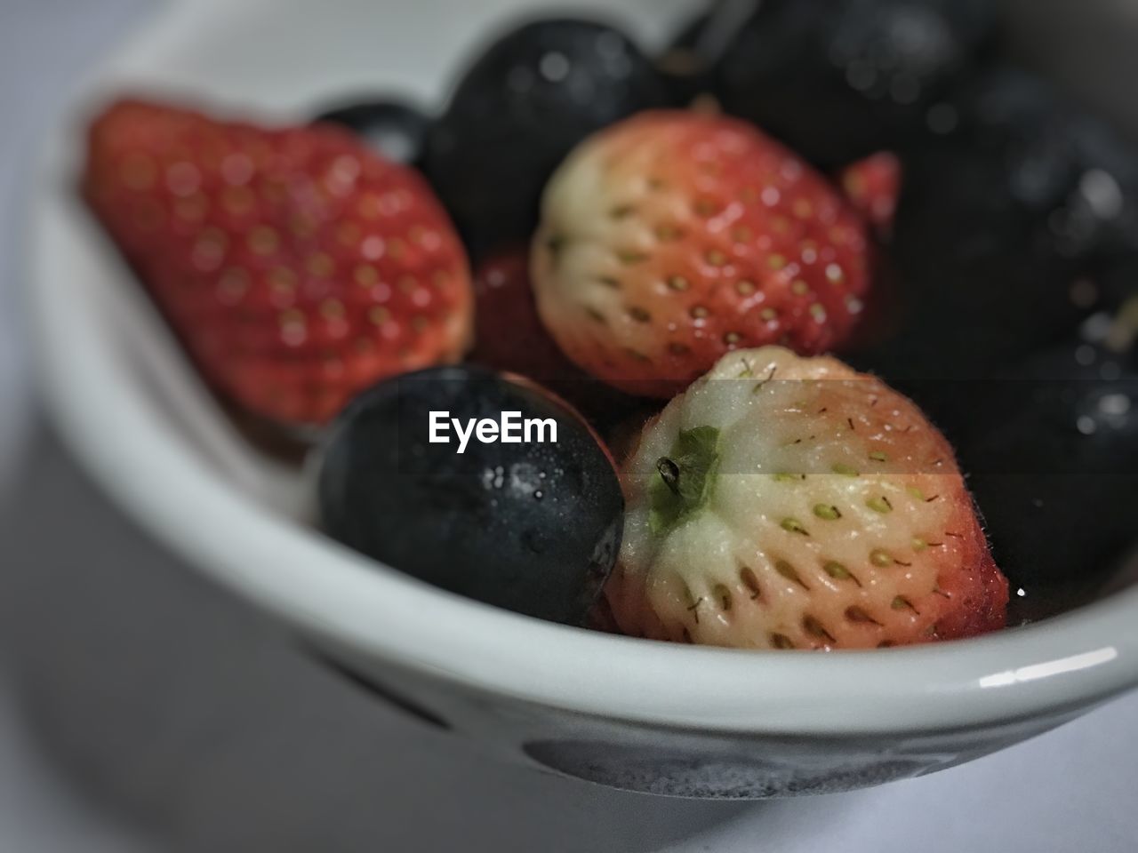 Close-up of strawberries and blueberries in bowl on table