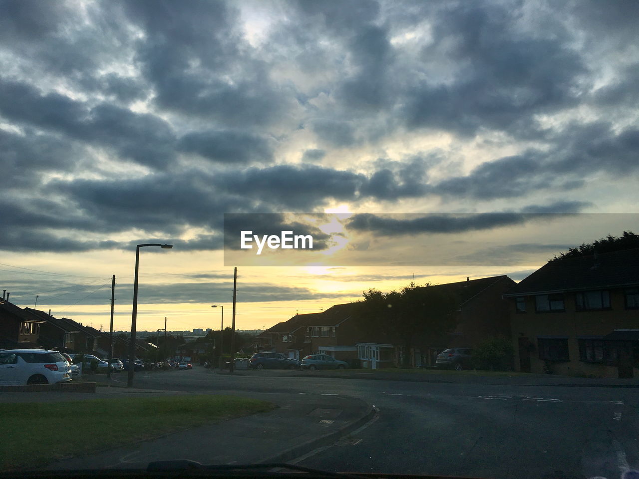 CAR ON ROAD AGAINST DRAMATIC SKY