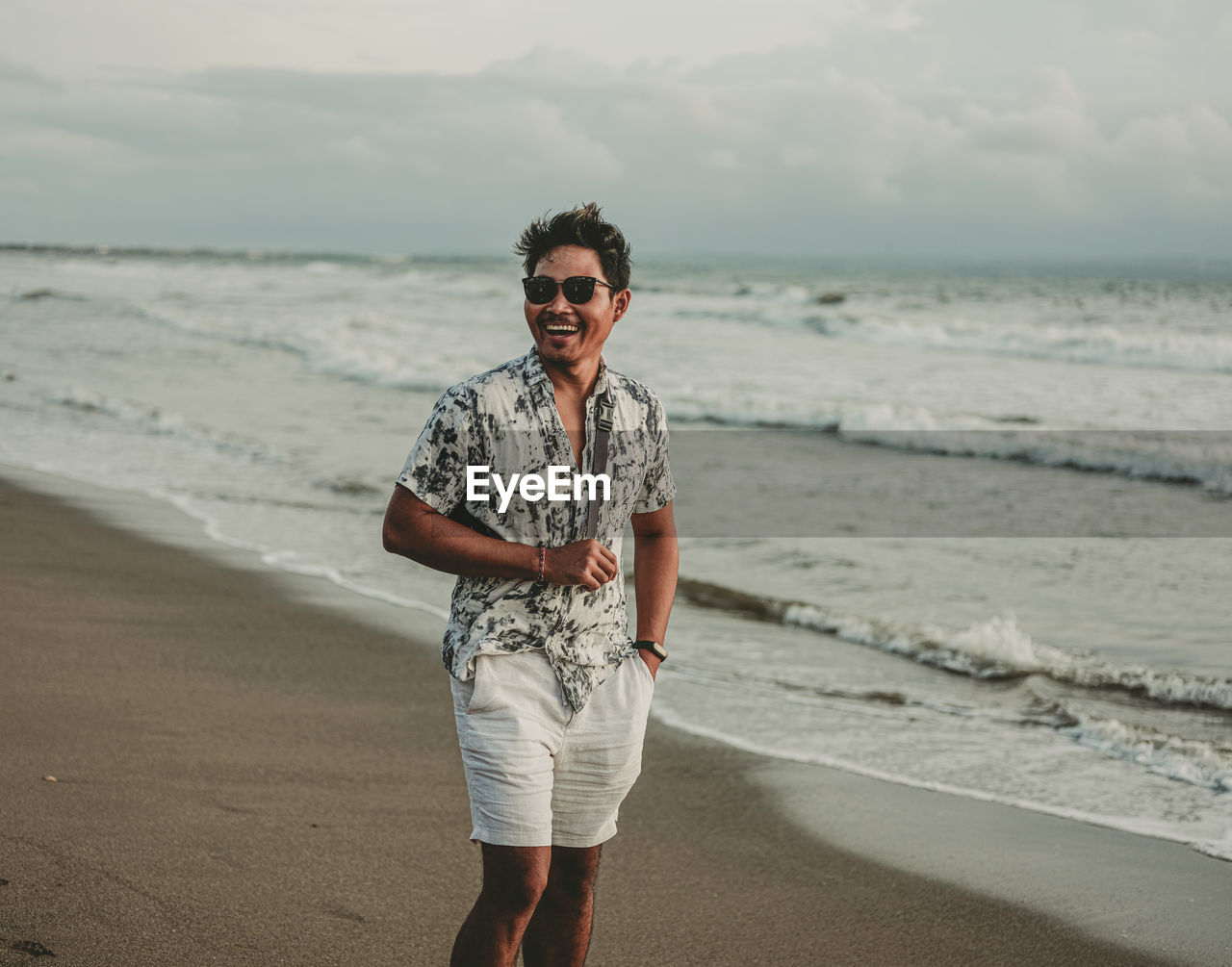 Full length portrait of smiling man standing on beach