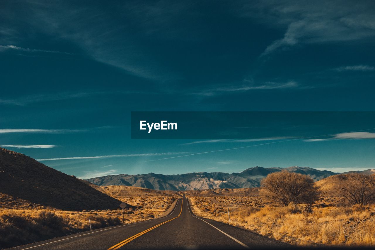 Empty road along landscape against sky