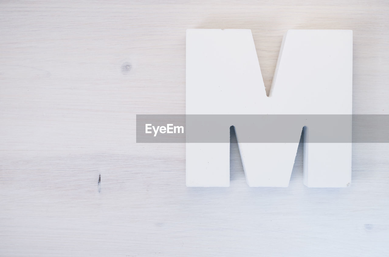 Directly above view of white letter m on wooden table