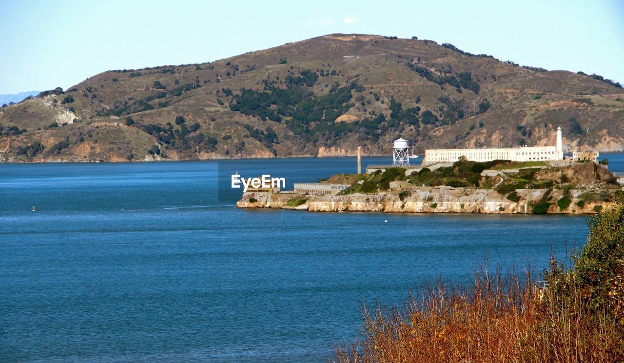 Alcatraz island amidst river in front of mountains