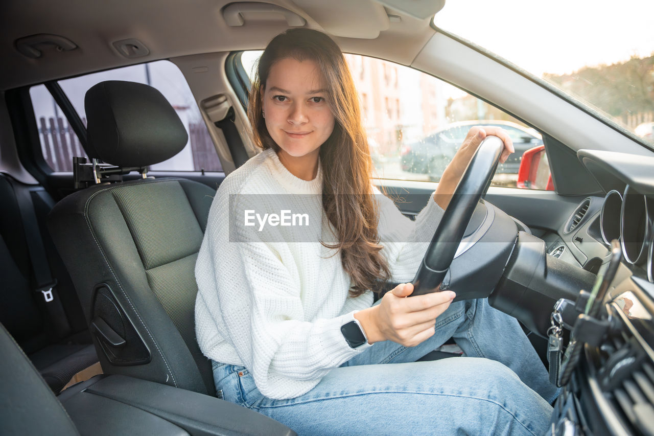 portrait of young woman using mobile while sitting in car