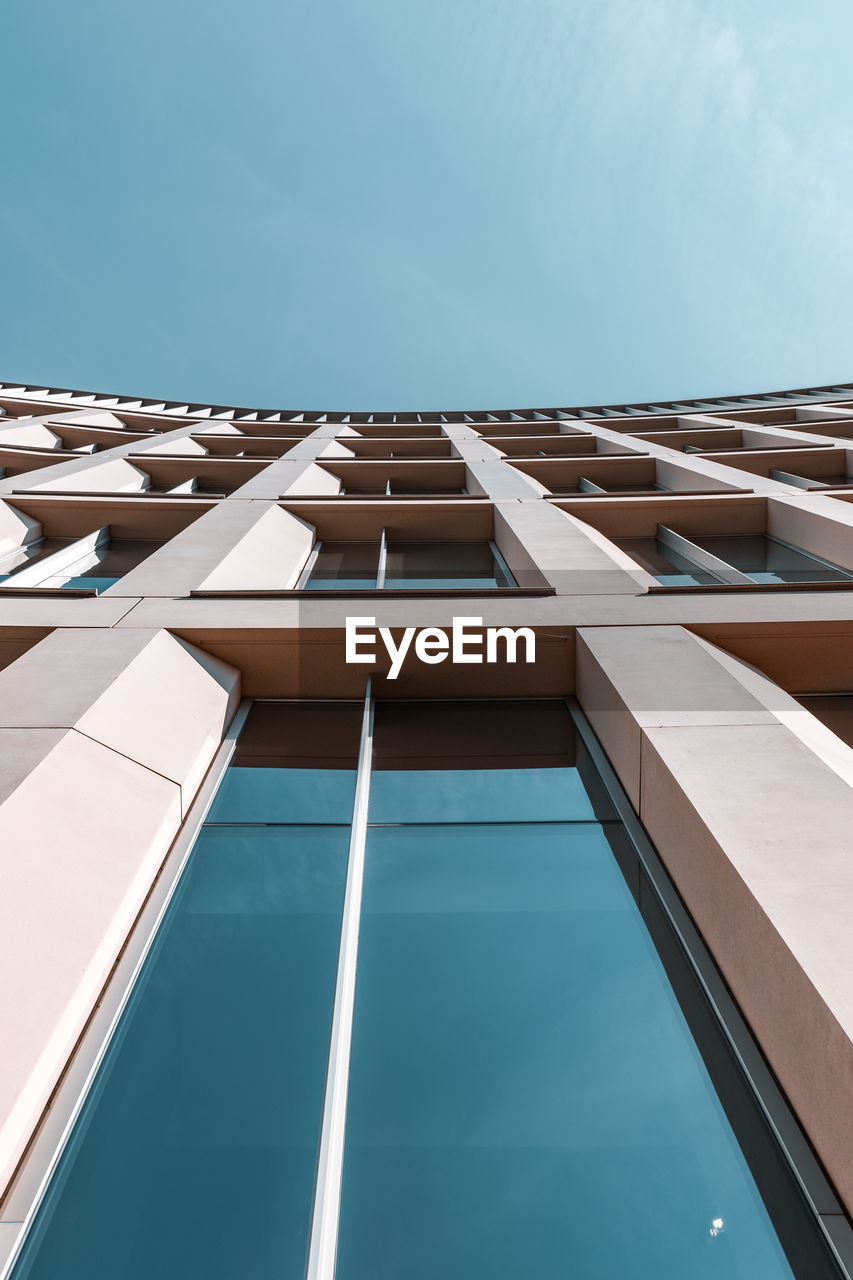 View looking up at building with tap windows against blue sky