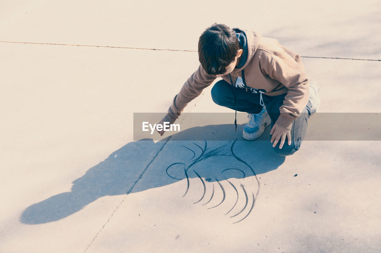 High angle portrait of child drawing in the street