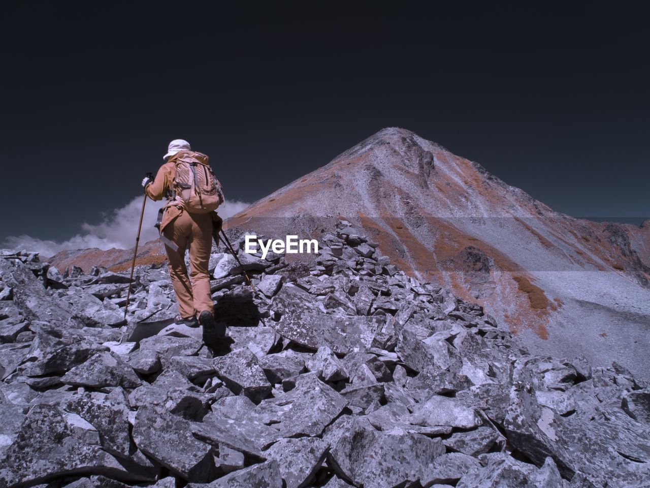 Low angle view of woman standing on rock against sky