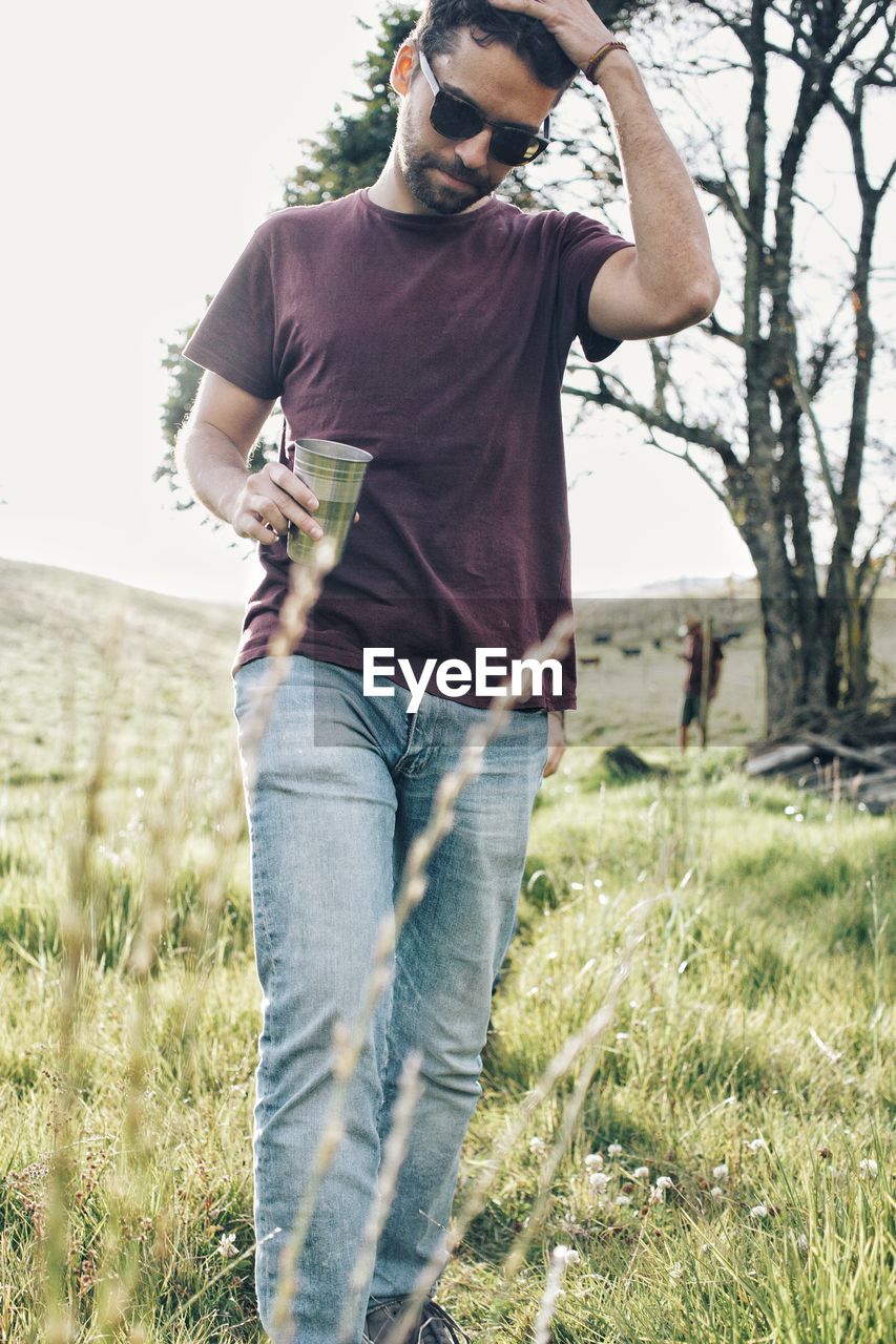 Young man wearing sunglasses while walking on field