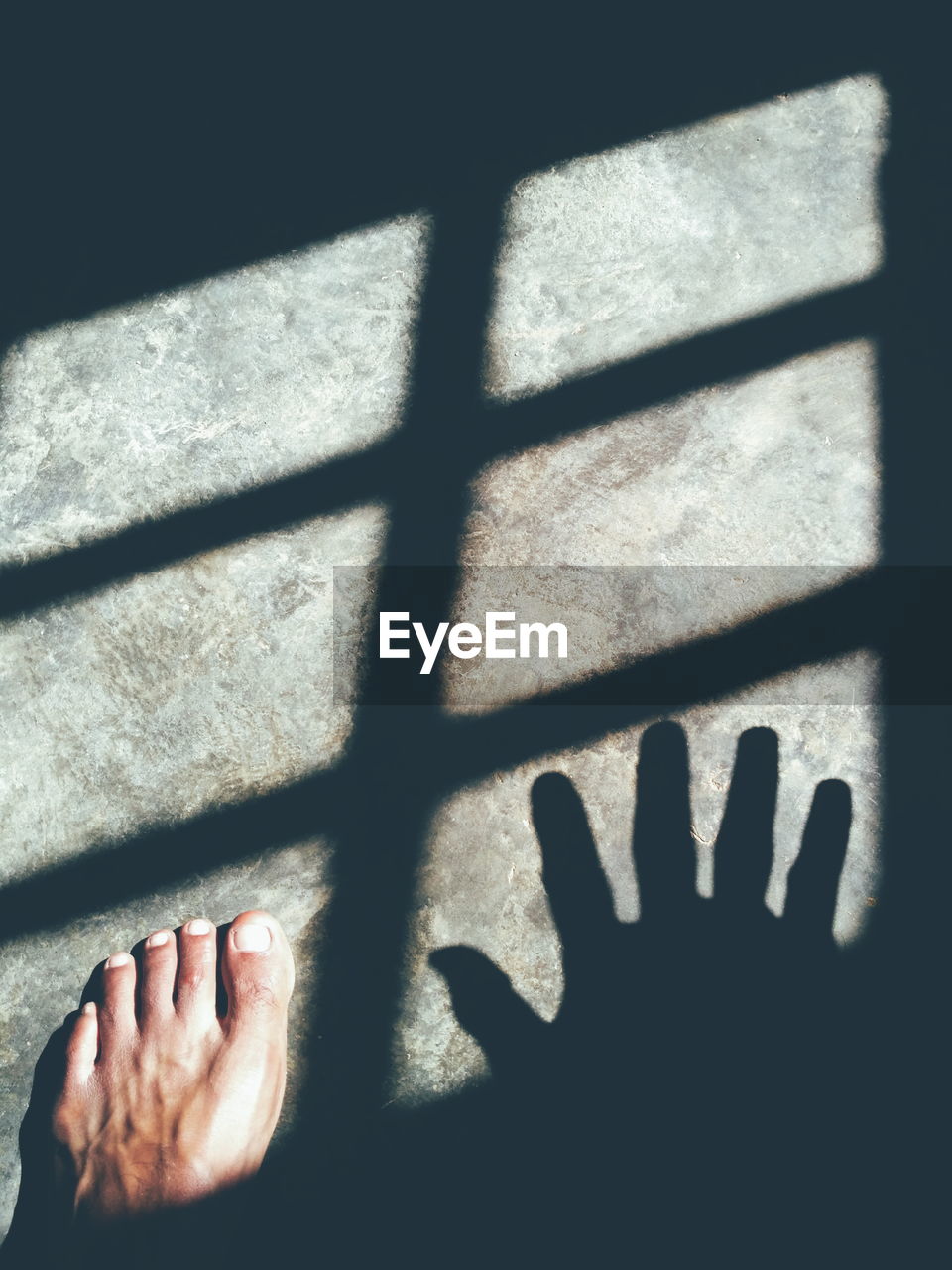 Low section of man standing on floor with shadows