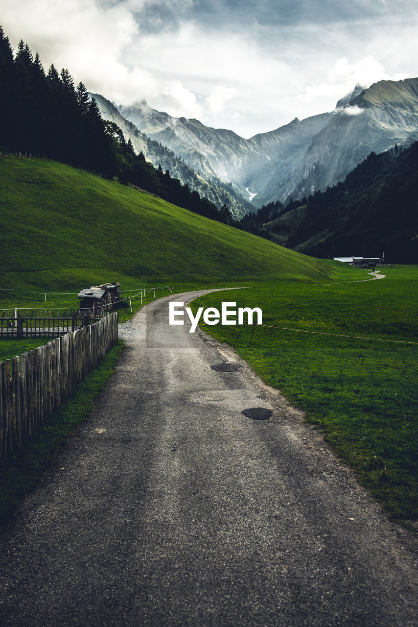 Road leading towards mountains against sky