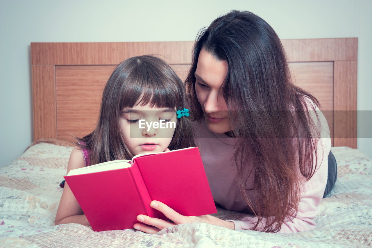 close-up of young woman using laptop while lying on bed at home