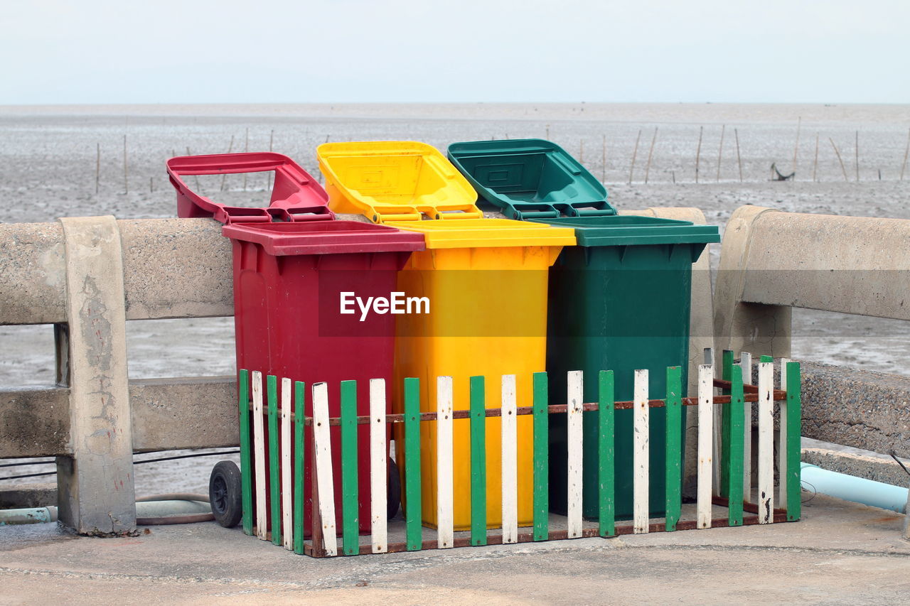 Multi colored garbage bins by railing