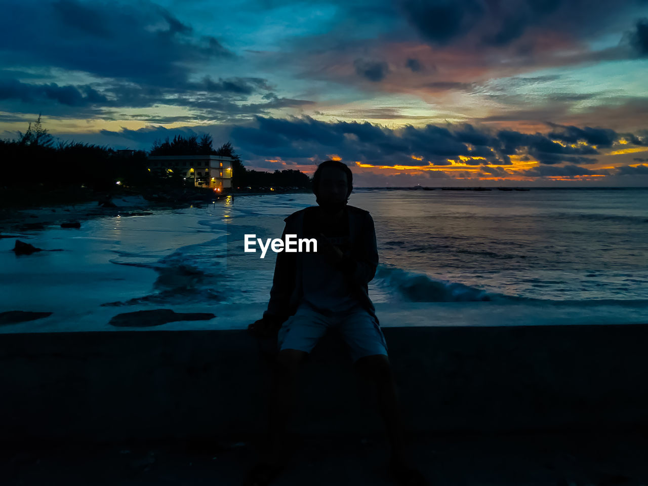 Rear view of silhouette man standing at beach during sunset