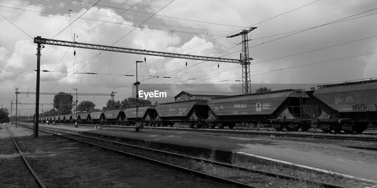 TRAIN IN RAILROAD STATION AGAINST SKY