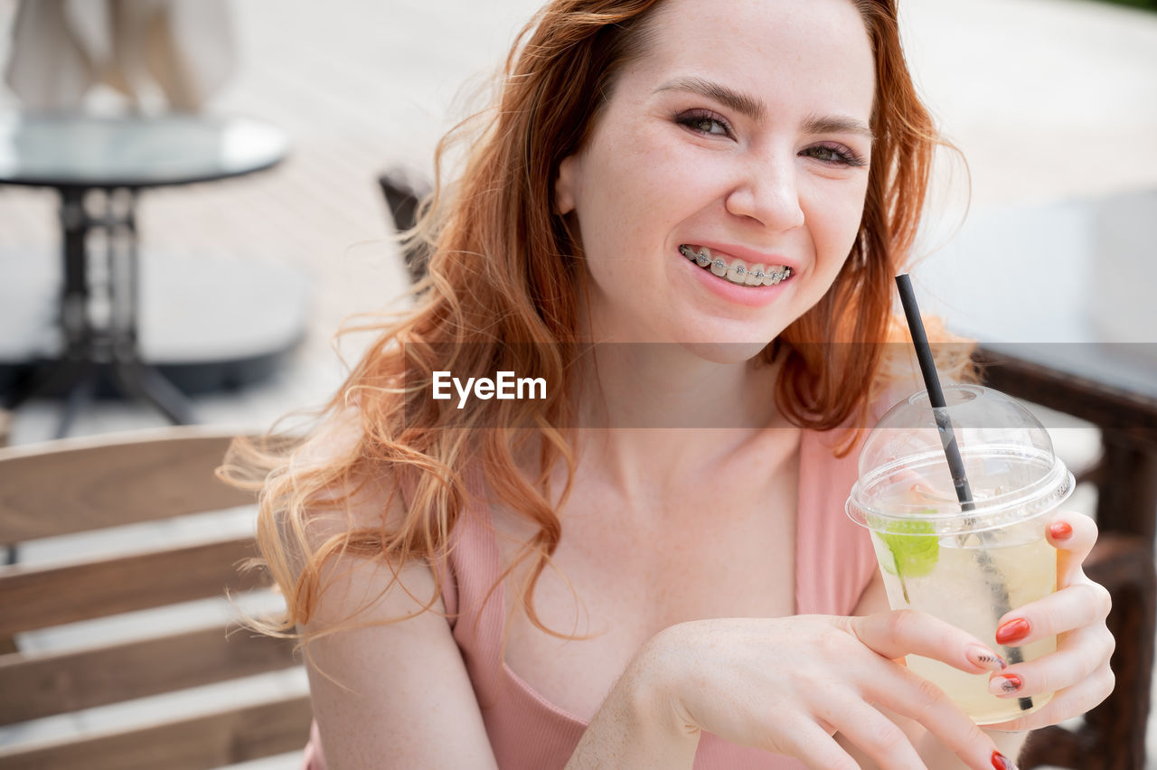 portrait of smiling young woman drinking glass