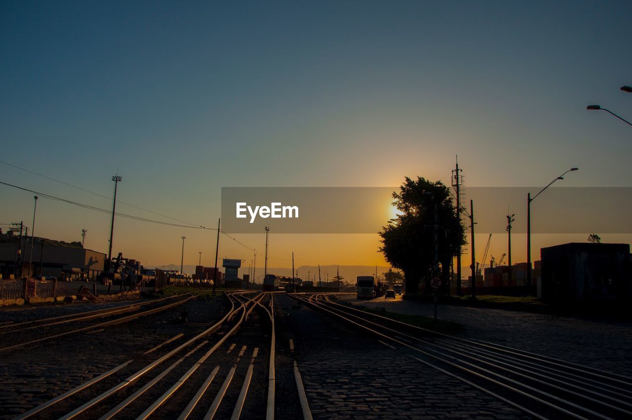 Railway tracks against clear sky during sunset