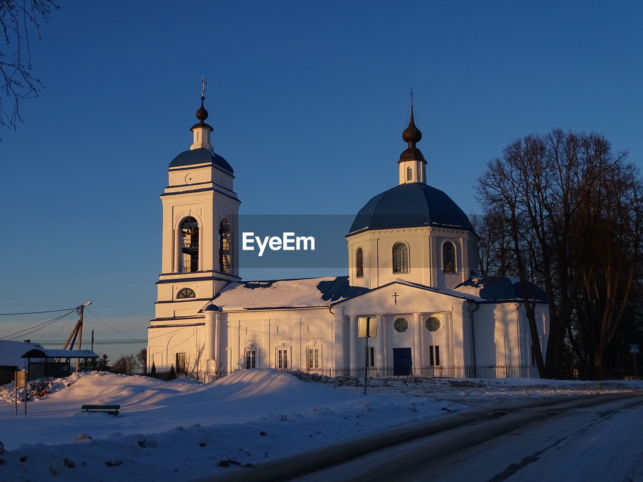 Church by building against clear blue sky during winter