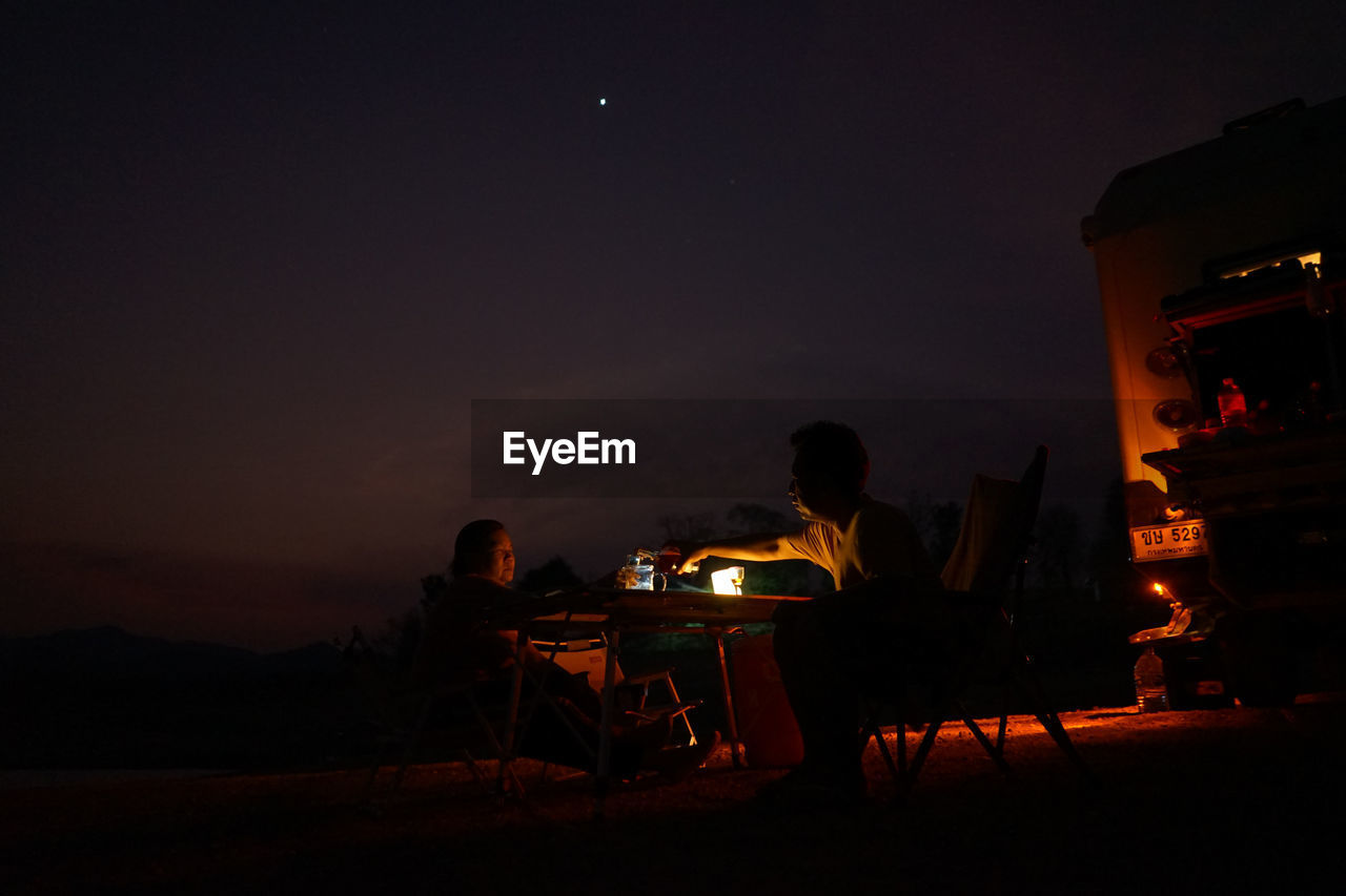 SILHOUETTE PEOPLE SITTING BY CHAIRS AT NIGHT