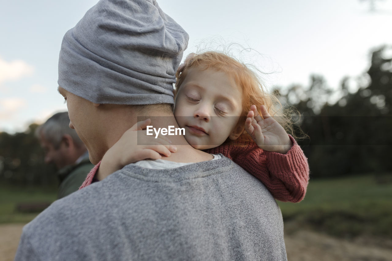 Father carrying daughter with eyes closed